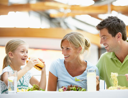 Kids Eat Free Orlando- Girl Eating A Burger With Parents